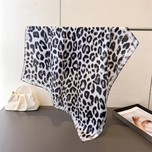 Detail showing high-quality black and white leopard print scarf with silky texture and drape