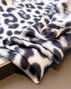 Macro detail of leopard print silk scarf showing soft fabric texture and glossy finish