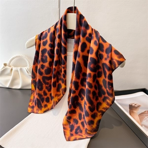 Leopard print silk scarf in orange and brown draped over a white dress with accessories