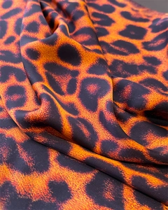 Detail shot of leopard print satin fabric in bright orange and black colors
