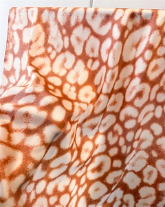 Macro detail of leopard print satin scarf showing silky texture and warm brown tones