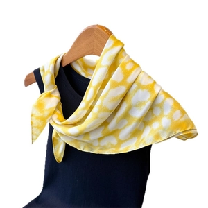 Elegant yellow and white heart print silk scarf tied on a hanger for styling display