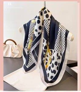 Close-up of silk scarf with polka dot and chain print on a white hanger