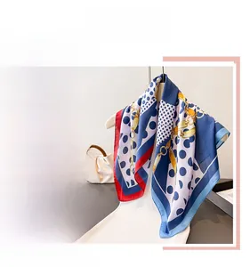 Detailed view of polka dot and gold chain print silk scarf with luxury red border