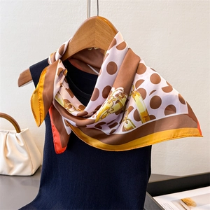 Close-up of silk-feel square scarf with polka dots, gold chains and orange borders
