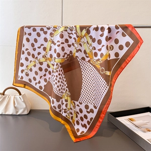 Satin square scarf with polka dots and gold chain print draped on a metal rack