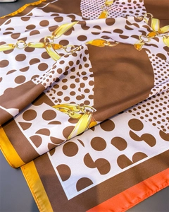 Detailed close-up of silk-like scarf with polka dots and golden chain print patterns