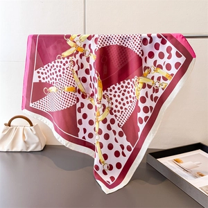 Detail of silk-like square scarf with red polka dots and golden chain print patterns
