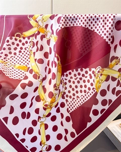 Close-up of burgundy silk scarf featuring white polka dots and gold chain print details