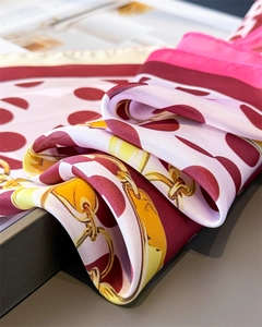 Detail of silk scarf showing red polka dots and golden chain print with satin luster