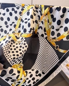 Close-up of silk scarf featuring polka dots and golden chain print with elegant draping