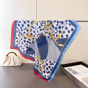 Detailed view of navy blue silk square scarf with polka dot and gold chain print patterns