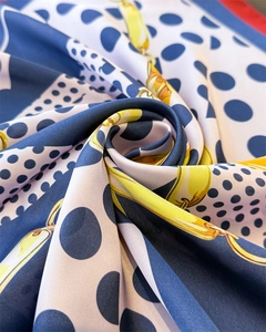 Macro view of silky scarf showing elegant gold chain and blue polka dot print details