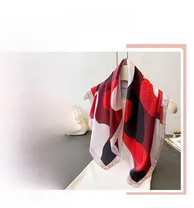 Detail of red and black abstract silk-like scarf draped over a gold hanger and flat