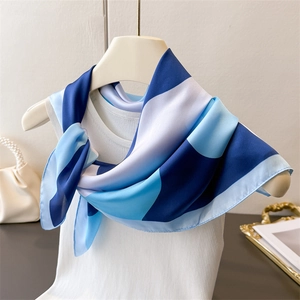 Detailed view of geometric pattern silk scarf styled on a white knit vest