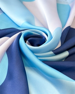 Detailed close-up of blue and white geometric silk fabric with elegant draped texture