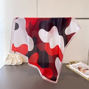 Close-up of abstract red and black print silk scarf hanging on a metal rod with a pearl bag