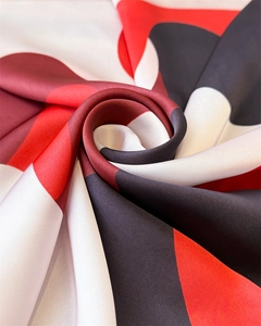 Macro detail of silk satin scarf with red and black geometric pattern and glossy texture