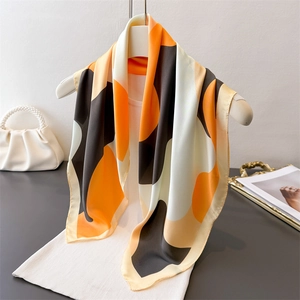 Minimalist geometric silk scarf with orange and black dot patterns on a hanger display