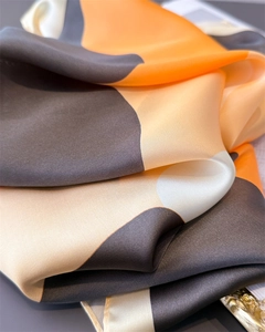Detailed macro shot of silky satin fabric with orange and brown color blocking folds