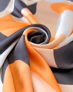 Macro shot showing the silky texture and elegant draping of the satin geometric scarf