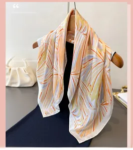 Vue détaillée d'un foulard léger à imprimé feuilles tropicales sur un cintre en bois