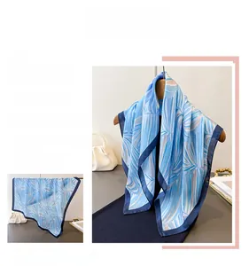 Détail du foulard en soie bleue avec motifs de palmiers blancs et bordure marine