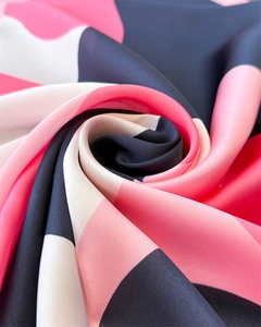 Macro detail of silky satin fabric showing pink and black color block stitching texture