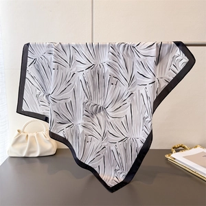 Détail du foulard en satin avec imprimé feuilles tropicales et bordure noire