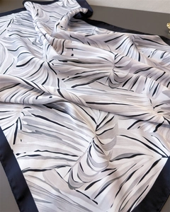 Détail d'un foulard en soie avec motifs de feuilles de palmier et bordures noires élégantes