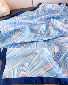 Vue détaillée du foulard en soie bleu clair avec motifs tropicaux et finition satinée