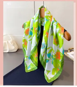 Detailed view of floral silk scarf featuring vibrant green and orange blossom prints
