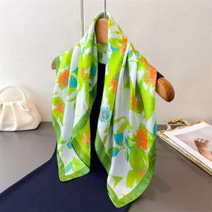 Elegant silk-like square scarf featuring vibrant green and orange floral print patterns