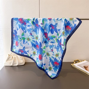Detailed view of the elegant blue floral silk scarf draped with smooth texture and gloss