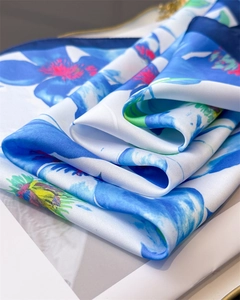 Close-up of silk scarf with floral print and navy blue borders showing soft texture