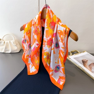 Floral print silk-like square scarf in vibrant orange and yellow on a black dress