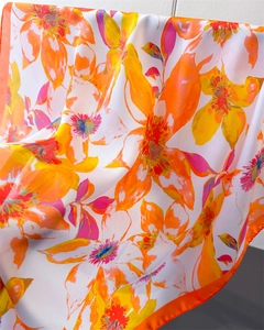 Detail of vibrant floral print silk scarf with high-quality orange rolled hem finish