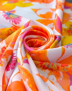 Macro view showing smooth silk texture and vibrant abstract floral print of the scarf