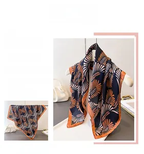 Dettaglio del motivo di un foulard in seta con foglie arancioni su fondo blu