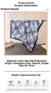 Dettaglio di un foulard in raso stampato con motivi astratti di piume blu e nere
