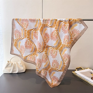 Dettaglio di un foulard di seta con motivi arancioni e oro, drappeggiato su un'asta di metallo