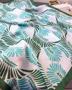 Dettaglio di un elegante foulard in seta con foglie verdi e raffinato bordo arrotolato