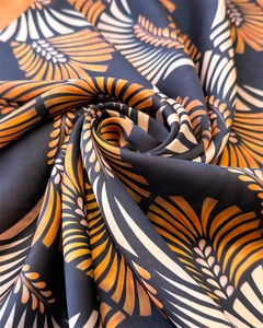 Dettaglio macro di foulard in seta nera lucida con stampa floreale arancione vibrante