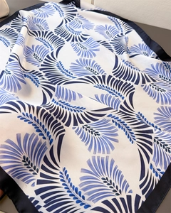 Dettaglio macro di foulard in seta con motivi astratti blu navy e bordi finemente cuciti