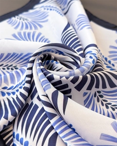 Dettaglio macro di sciarpa in seta blu e bianca con motivo a spirale e trama morbida