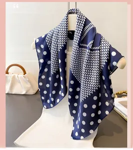 Close-up of navy blue silk-feel scarf with white polka dots and geometric mesh patterns