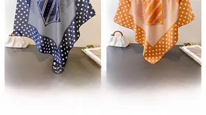 Detail of silk-like square scarves in navy and orange featuring white polka dots pattern
