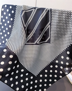Detailed close-up of geometric polka dot and stripe silk scarf with soft fabric folds