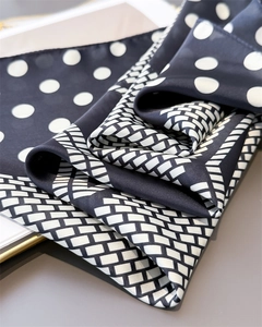 Macro detail of silk-like satin scarf showing polka dots and geometric patterns