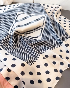 Detail of cream white silk scarf with navy polka dots and geometric square patterns